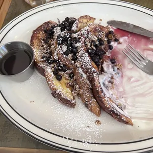 a plate of french toast with blueberries and powdered sugar