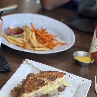 Prime rib grilled cheese sandwich with half order of sweet potato fries and half French fries.