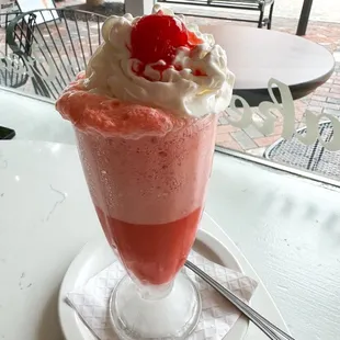 a strawberry milkshake with whipped cream and a cherry on top