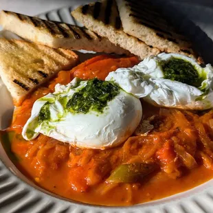 Shakshuka, poached eggs with pesto over a stew