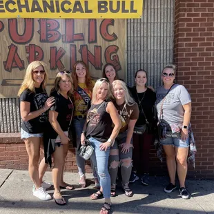 a group of women standing in front of a public parking sign