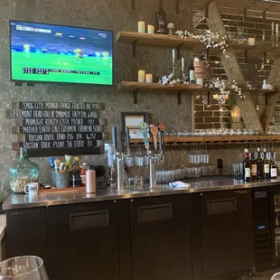 a bar with wine glasses and a television