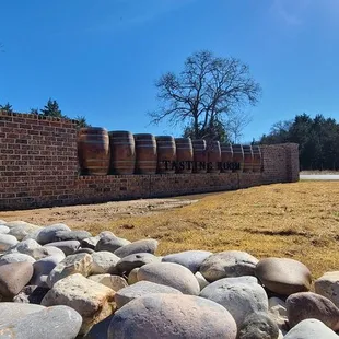 a brick wall with a row of wine barrels in the background