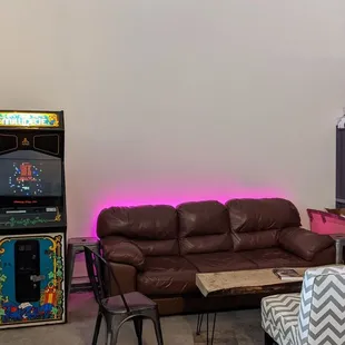 a living room with a couch, chair, and arcade machine