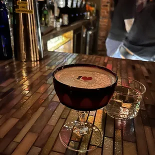 a cocktail in a coupe glass on a bar