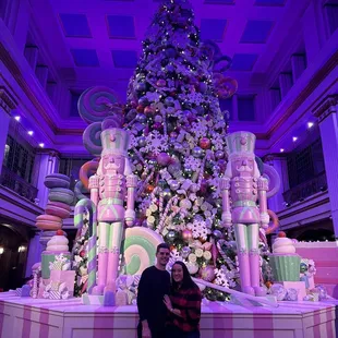 two people standing in front of a christmas tree