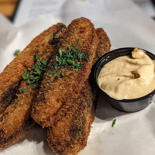 a plate of fried fish with a side of dip