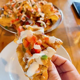 a hand holding a piece of nachos