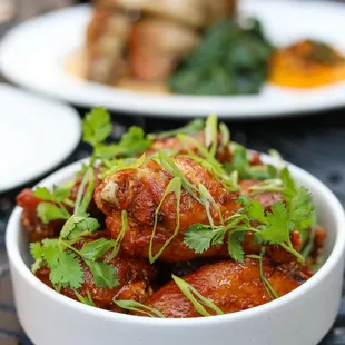 a bowl of chicken wings with garnish
