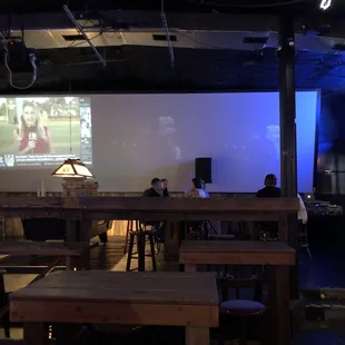 a man sitting at a table in front of a projector screen