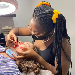 Esthetician tweezing lip hair.