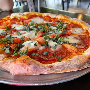 a pizza with pepperoni, basil and mozzarella