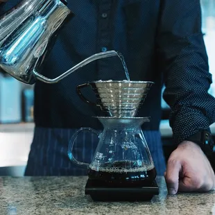 a person pouring water into a coffee pot