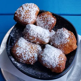 a plate of powdered sugared donuts