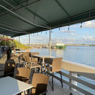 tables and chairs on a patio overlooking the water