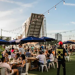 a crowd of people sitting at tables under umbrellas