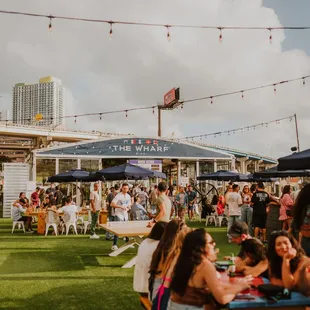 a crowd of people sitting at tables under umbrellas