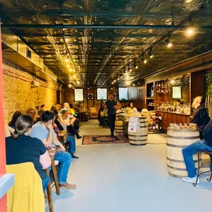 a group of people sitting at tables in a wine cellar