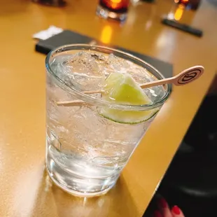 a glass of alcohol with a lime wedge