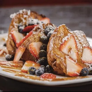 Hawaiian French Toast- Hawaiian Bread, French Toast Battered, Coconut Shavings, Strawberries, Blueberries, Caramel &amp; Powdered Sugar.