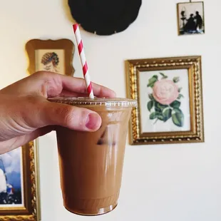 a hand holding a cup of iced coffee