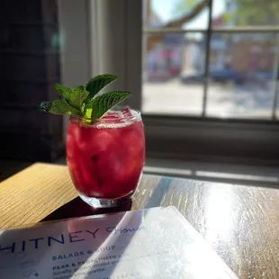 a drink on a table in front of a window