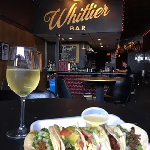 a plate of tacos and a glass of wine