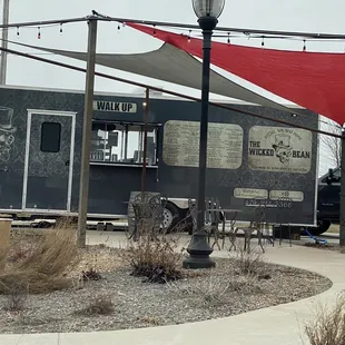 a black food truck with a red awning