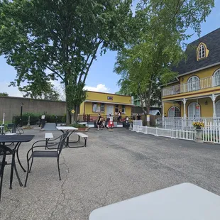 tables and chairs outside of a yellow house