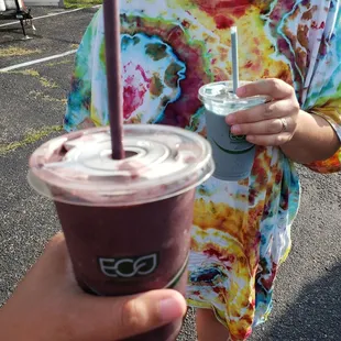 a woman in a tie dye shirt holding a drink