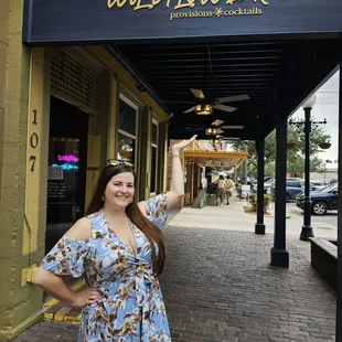 a woman in a blue dress standing in front of a store