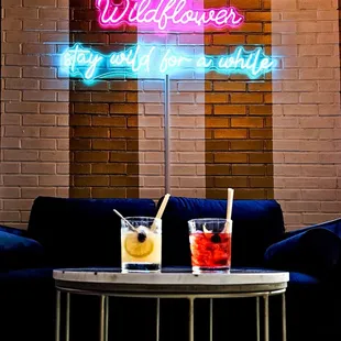 two cocktails on a table in front of a brick wall