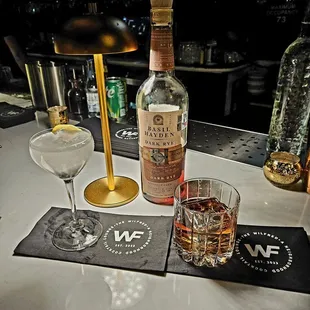 a bottle of whiskey, two glasses, and a drink