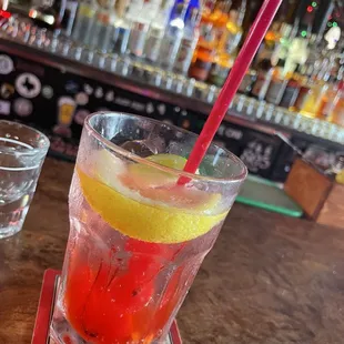 a glass of water with a straw and a slice of lemon