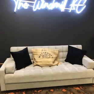 a couch with pillows and a neon sign
