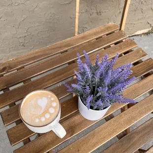 Latte art in a mug on a patio table with plant