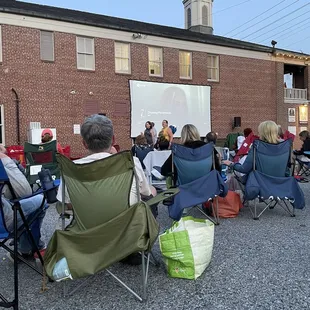 people sitting in lawn chairs watching a movie