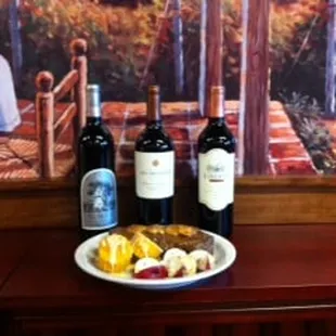 three bottles of wine and a plate of fruit