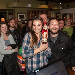 a group of people holding up a bottle of wine