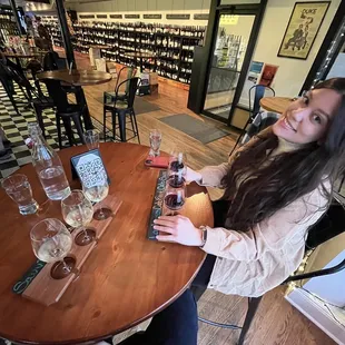 a woman sitting at a table with wine glasses