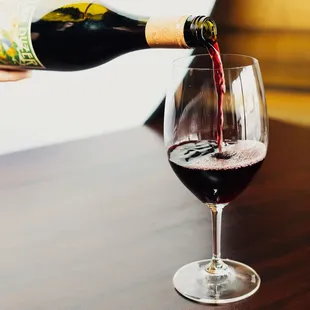 a person pouring a glass of wine