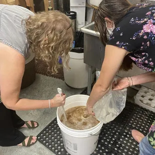 a woman pouring wine into a bucket