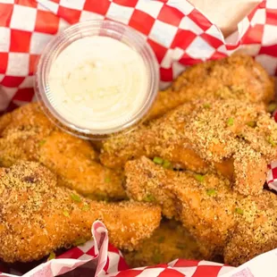 a basket of fried chicken with a dipping sauce