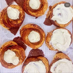 a tray of cinnamon rolls with cream frosting