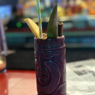 a purple tiki cup with straws