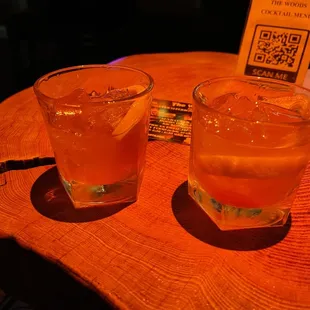 two glasses of orange juice on a wooden table
