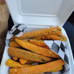 a takeout container filled with fried zucchini sticks
