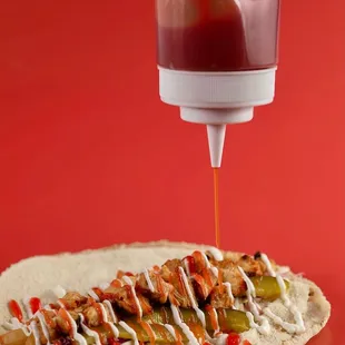 a ketchup being drizzled over a pita