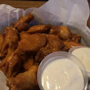 a basket of chicken wings with ranched dips
