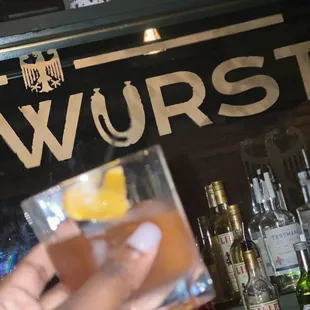 a person holding a drink in front of a bar